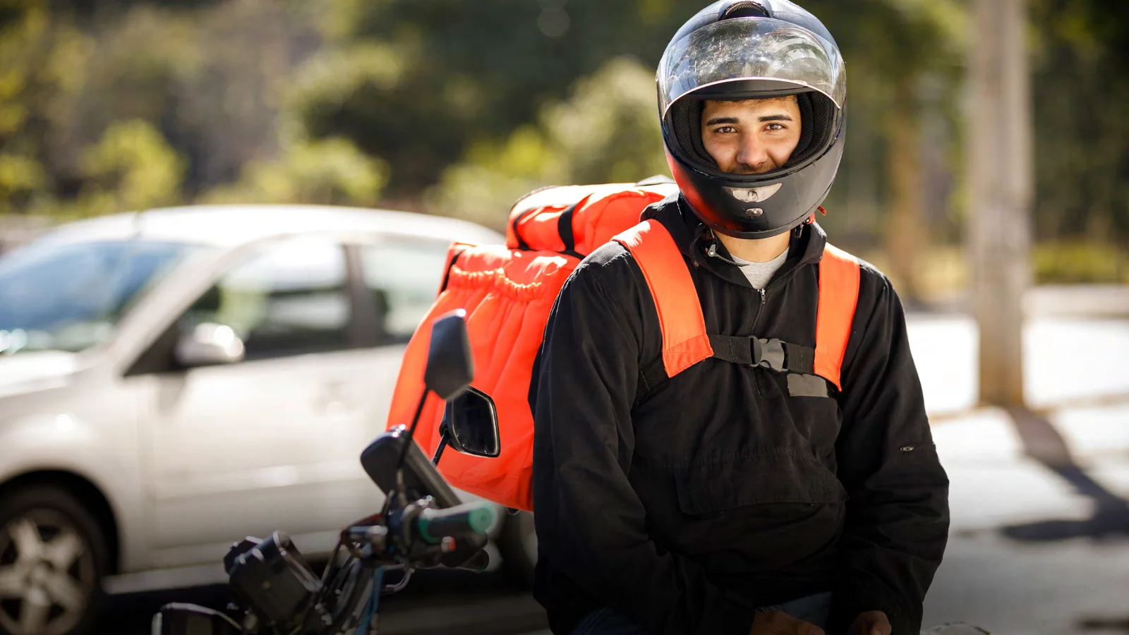 Motociclista entregador com baú, usuário final das peças Rakum